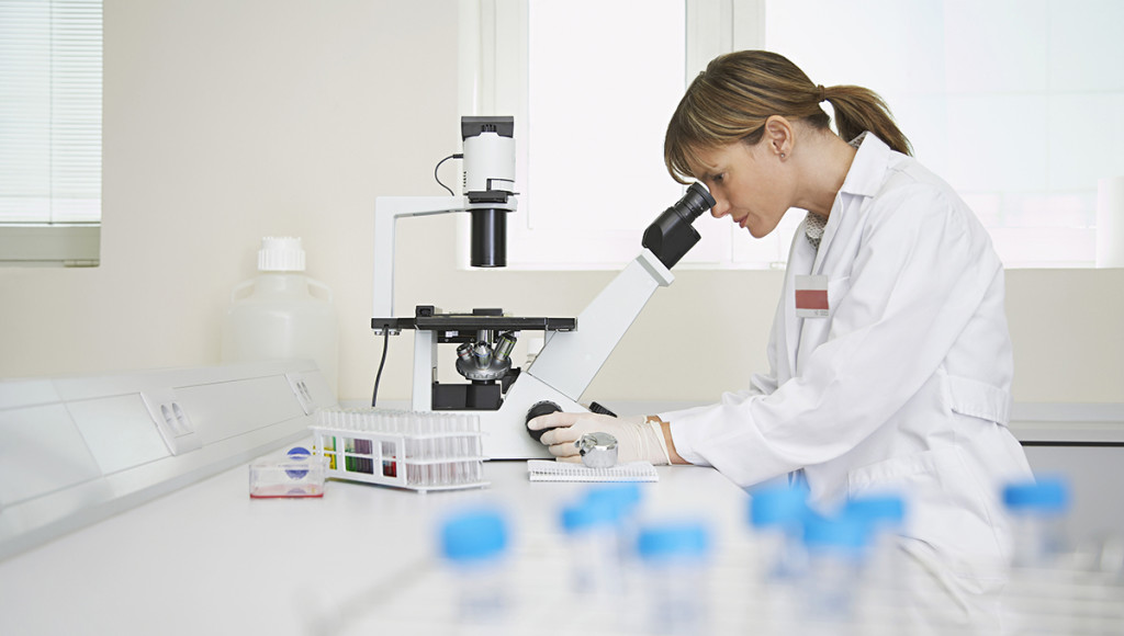Side view of a female scientist looking in microscope in laboratory